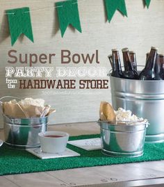 some beer bottles are sitting in buckets on a table with green grass and bunting