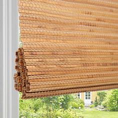 a close up of a window with a bamboo blind in the middle and green grass behind it