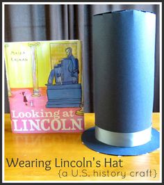 a paper hat sitting on top of a wooden table next to a book and an image of abraham lincoln