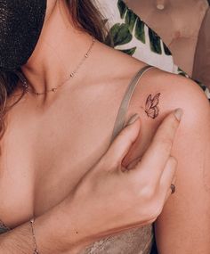 a woman with a small tattoo on her left arm holding onto the other side of her shoulder