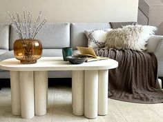 a living room with a couch, coffee table and vases on the tables in front of it