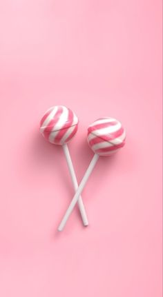 two lollipops sitting on top of each other in front of a pink background