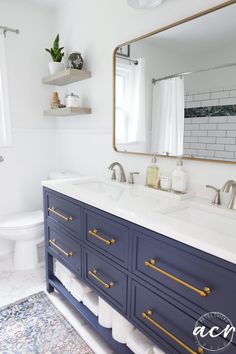 a white and blue bathroom with gold trim on the vanity, mirror over the sink