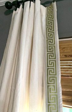 the curtains are hanging in front of the window with roman key design on them,