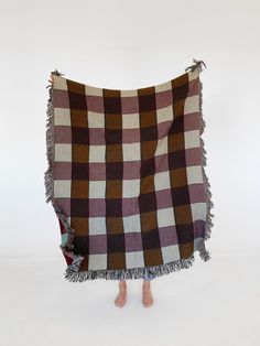 a woman is standing under a blanket that has fringes on the bottom and sides