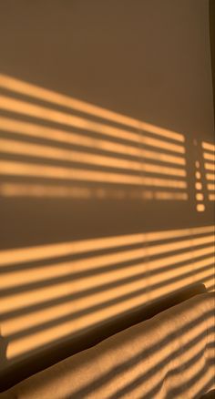 the sun is shining through blinds on a window sill in front of a bed