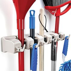 there are several different types of brooms and mop hooks on the wall,