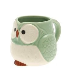 a green and white owl mug sitting on top of a table