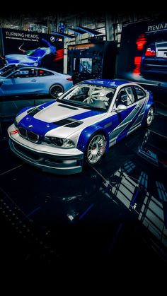 a blue and white car is on display in a showroom with other cars behind it