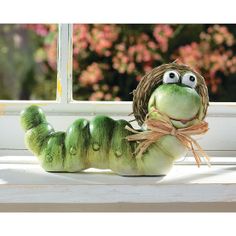 a stuffed animal caterpillar sitting on top of a window sill