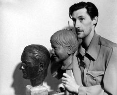 a black and white photo of a man standing next to a bust of a woman