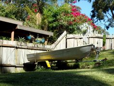 a boat sitting on the grass next to a fence