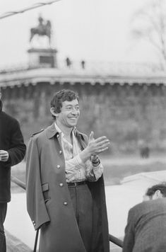 two men standing next to each other in front of an airplane and one man is holding his hands out