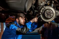 a man working on the front wheel of a car