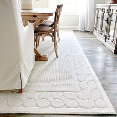 a living room with a white rug on the floor next to a table and chairs