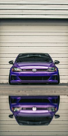 a purple car parked in front of a garage door with its reflection on the ground