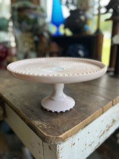 a white cake plate sitting on top of a wooden table