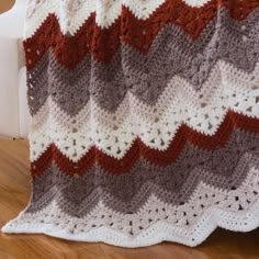 a crocheted blanket sitting on top of a wooden floor next to a white chair