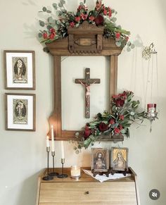 an old dresser with flowers and candles on it is displayed in front of a cross