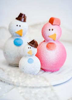 three frosted snowmen sitting on top of a white plate next to each other