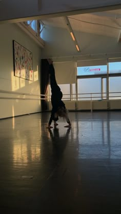 a person doing a handstand in an empty room with large windows on the side