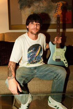 a man sitting on top of a couch holding an electric guitar in front of his face