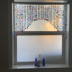 a window with beads hanging from it's side and bottles on the windowsill