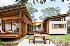 an outdoor area with tables, chairs and a house in the background that is surrounded by trees