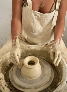 a woman in an apron working on a potter's wheel