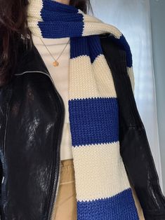 a woman wearing a black leather jacket and a blue and white knitted striped scarf