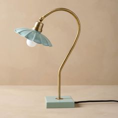 a table lamp with a blue glass shade on it's base and a black cord