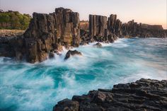 the ocean is blue and choppy with rocks sticking out of it's sides