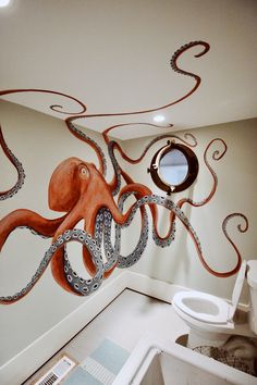 an octopus painted on the wall in a bathroom with a toilet and sink below it