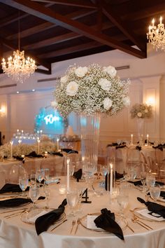 an elegant centerpiece with white flowers and black napkins sits atop a round table