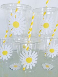 six plastic cups with yellow and white paper straws in them, decorated with daisies