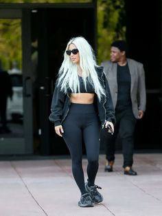 lady with long white hair wearing black sports bra and leggings walking down the street