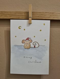 a christmas card with a mouse hanging on a clothes line and the words merry christmas written below it