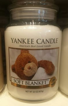 a yankee candle with a teddy bear on it in front of other candles for sale