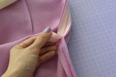 someone is sewing something on a piece of pink fabric with a pair of scissors next to it