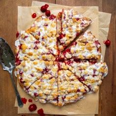 a cherry crumbled pizza on top of a piece of parchment paper with cherries around it