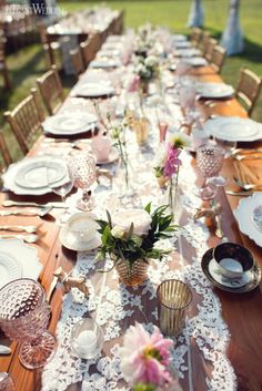 a long table is set with plates and flowers