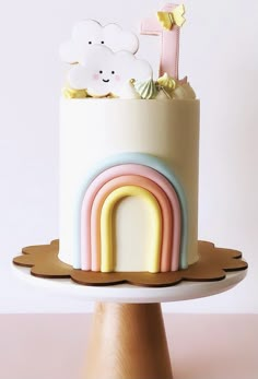 there is a cake that has a rainbow on the top and clouds on the bottom