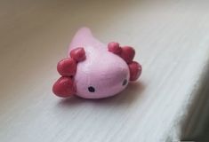 a close up of a pink toy animal on a white surface with black dots around it's eyes