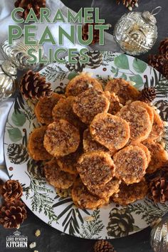 the cover of caramel peanut slices on a white and green plate with pine cones