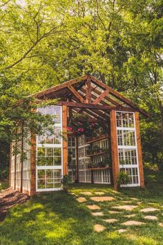 a small wooden structure sitting in the middle of a lush green field