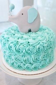 a blue cake with an elephant on top and swirly icing around the edges