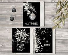 three black and white christmas cards with snowflakes hanging from the front, on a wooden background