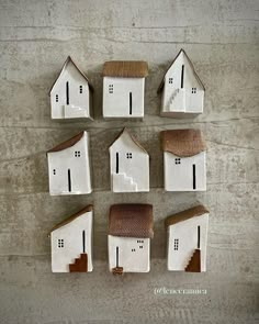 small white houses with brown roofs are arranged in a row on the wall, and one is made out of clay