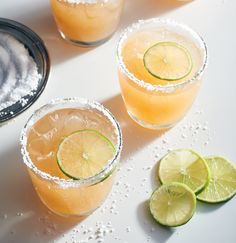 two margaritas with lime slices and sugar on the rim are sitting next to each other