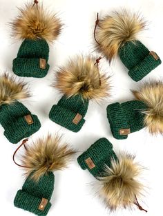 six green knitted hats with brown fur pom - poms on each one